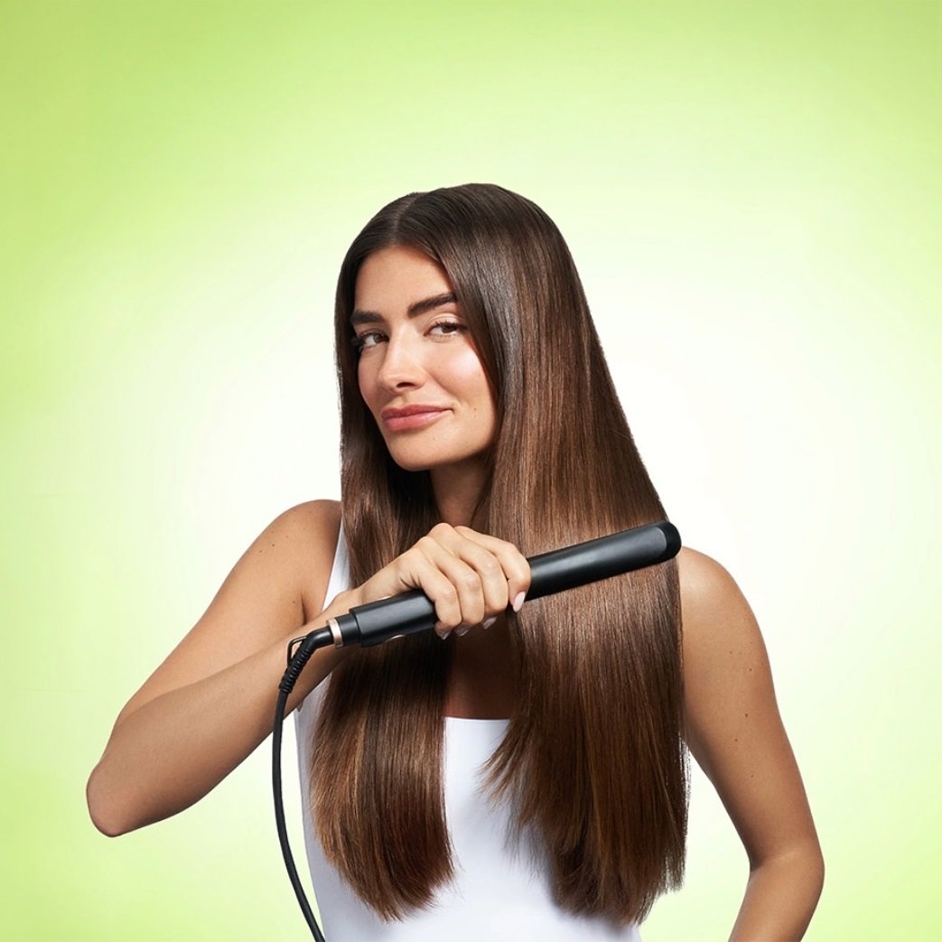 Brunette model facing forward as she straighten long, thick, smooth hair.
